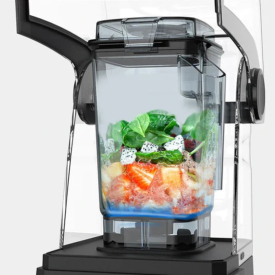 Eye-level front view of the Kuvings CB850 blender jar filled with fresh smoothie ingredients, including green spinach leaves, diced dragon fruit, and strawberries, with the sound shield open against a white background.
