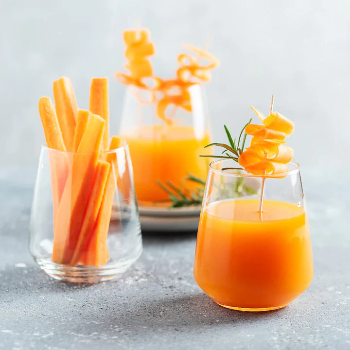 Zwei Gläser Orangensaft mit Karottensticks auf hellgrauem Hintergrund