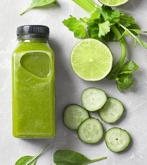 Grüner Smoothie in einer Flasche mit Limette, Gurke und Sellerie auf heller Oberfläche