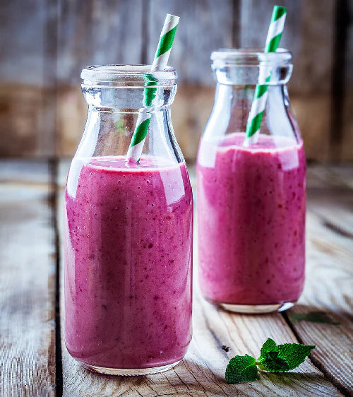 Zwei Glasflaschen gefüllt mit rosa Smoothie auf Holzoberfläche