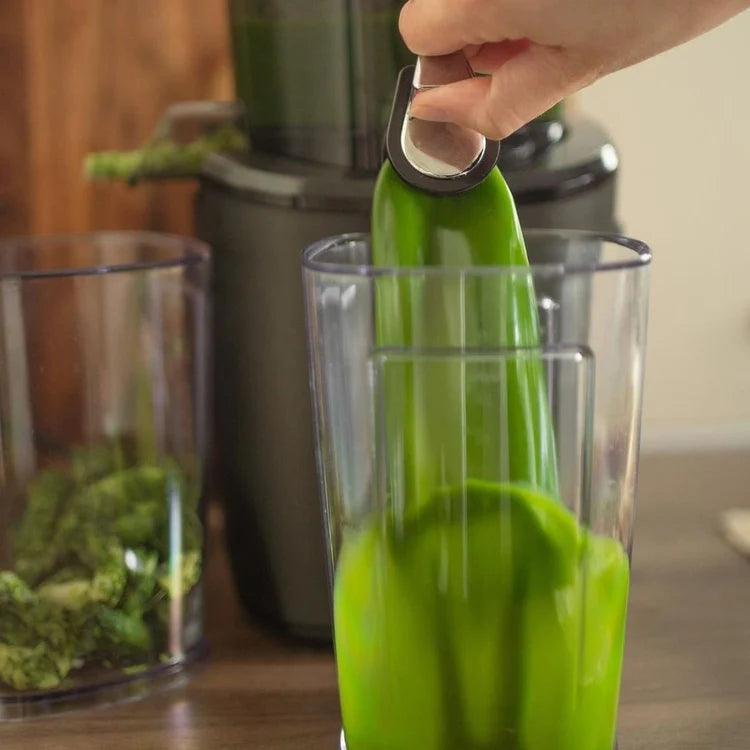 Kuchyňský odšťavňovač Kuvings použitý se skleněnou nádobou a mixérem v pozadí pro přípravu zdravých domácích šťáv a smoothies.